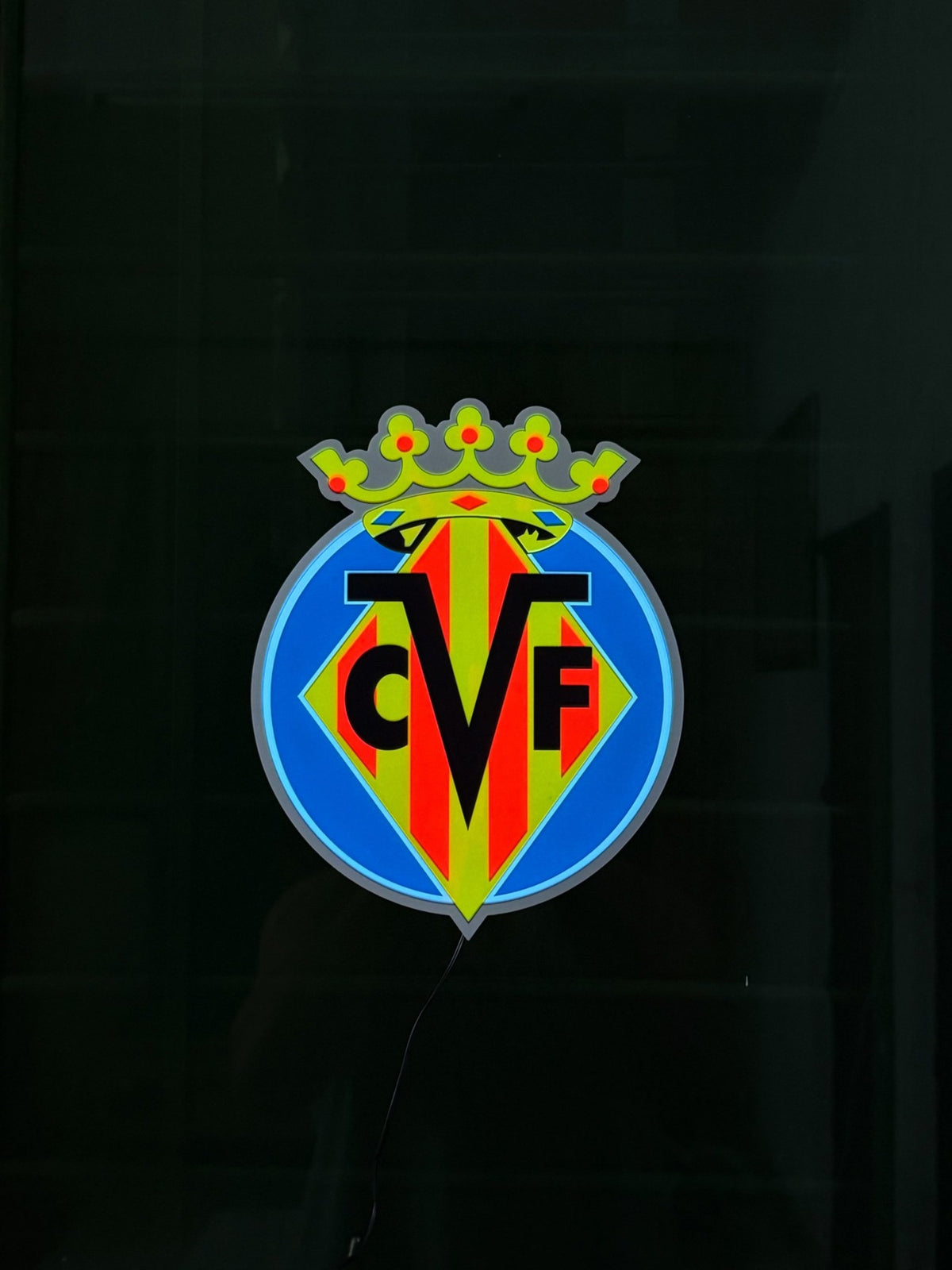 Escudo Luminoso Decorativo Villarreal CF encendido en una ventana